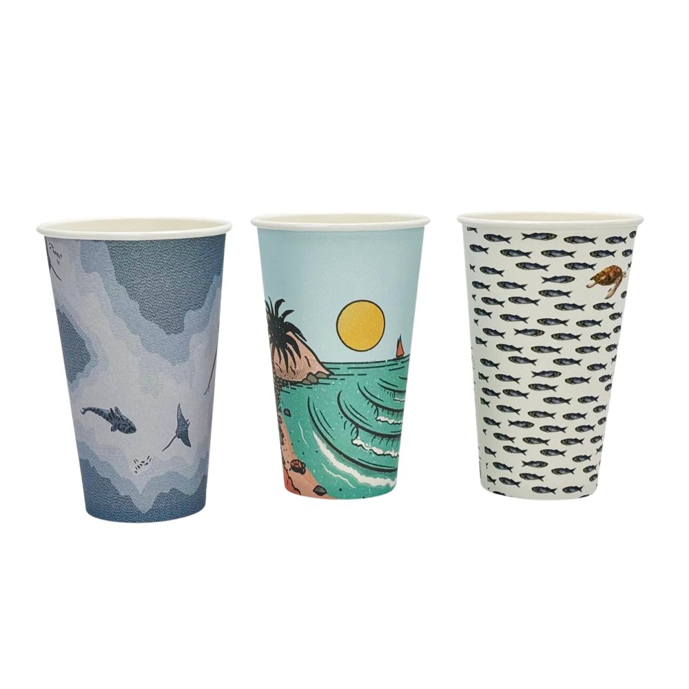 A set of three paper cups with different ocean-themed designs, including a whale, a sun and moon over a tropical scene, and a school of fish.