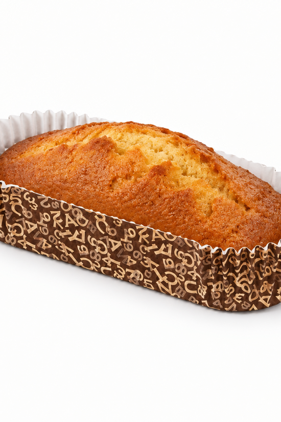 A golden-brown loaf of bread in a brown patterned paper liner with white fluted edges, photographed on a clean white background.